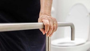 Old woman holding onto a safety rail