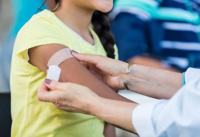Pediatrician applies bandage to patient's arm after an immunization