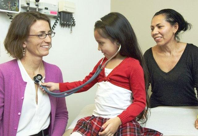 A child uses a stethoscope on a doctor during her wellness exam